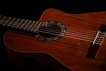 Fototapeta premium Classical Spanish flamenco guitar close up, dramatically lit isolated on black background with copy space.