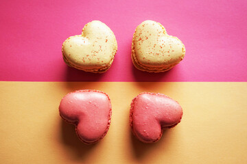 Macarons in the shape of hearts on a pink and yellow background