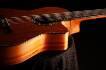 Obraz premium Classical Spanish flamenco guitar close up, dramatically lit isolated on black background with copy space.
