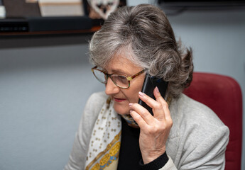 gray-haired businesswoman talking on smartphone