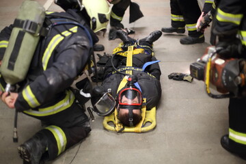 Firefighters in uniform are training to help suffer at subway, focus on belt.