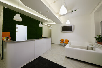 Interior of reception hall with front desk and sofas.