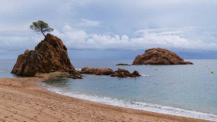 Golden beach in small Spanish town with rocks and island