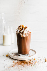 Chocolate milkshake with cream and hazelnuts in a white kitchen
