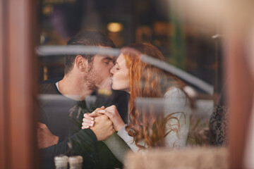 Couple, kissing and holding hands on date at cafe for bonding, romance and healthy relationship...