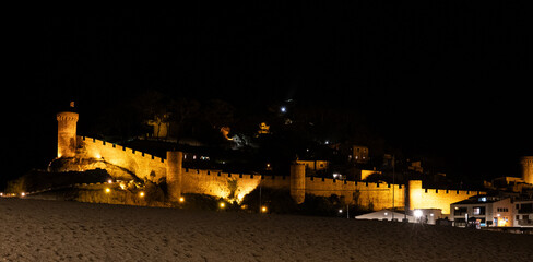 Lights illuminate coastal fortress walls in Spanish seaside town