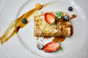 Layer cake decorated with mint, strawberry, blueberry and sauce on plate.