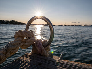 The sun glints on a chrome ring on a wooden pier.