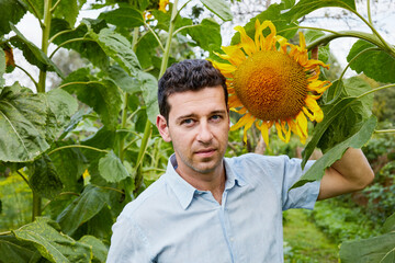 Young man with sunflower at vegetable garden.