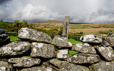 Old stone wall and fencepost on Datmoor in Devon with moorland in distance.