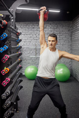 Man doing exercises with kettlebell in gym.