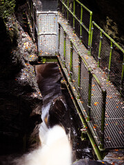 Metal bridge ober a mossy gorge with rushing water