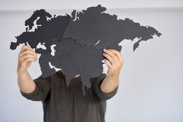 Man holds assembled puzzle map of Eurasia.