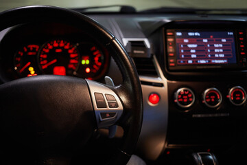 Steering wheel and glowing car dashboard, focus on wheel.
