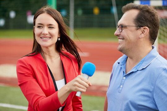 Young female journalist interviews man, focus on woman.