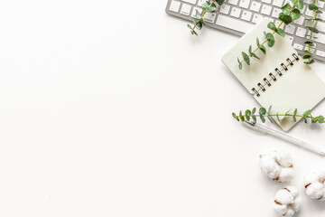 Laptop, cotton branch on white table flat lay copy space. Minimal freelancer home office desk workspace.