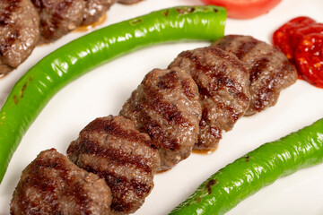Grilled meat balls. Turkish grilled meatballs with roasted peppers and tomatoes on wooden background. Close up