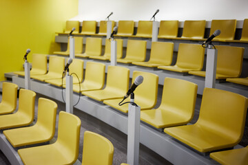 Yellow chairs and microphones in conference auditorium.