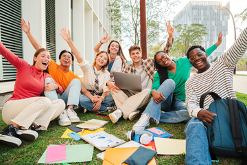 Portrait of a big group of happy teenage students sitting at university campus lawn, gesturing and celebrating together a academic goal. Positive multiracial teenagers gesturing and looking at camera