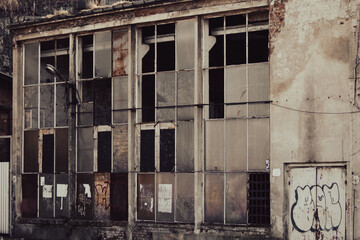 Abandoned factory building with broken windows and graffiti on the wall
