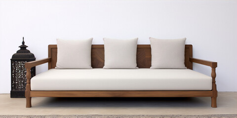 Minimalist wooden sofa with white cushions against a white wall with a lantern beside it.