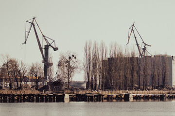 Abandoned industrial area with cranes on the bank of river
