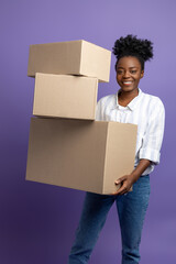 Dark-skinned young woman with boxes in hands looking contented