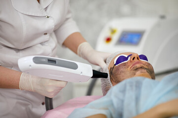 Cosmetician uses laser for epilate patient face in cosmetology office.