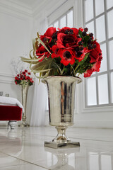 Bunch of artificial flowers and berries in vase on floor in bedroom.