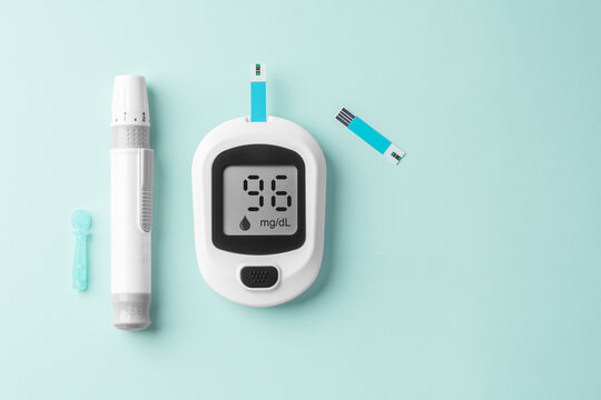 Glucometer, blood glucose sugar testing for diabetes on light green background
