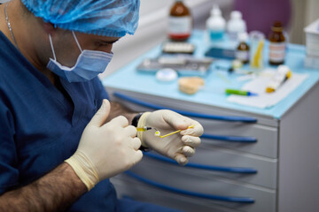 Dentist puts yellow gel on implant in stomatologist office.