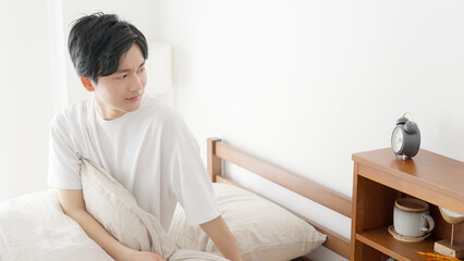 目覚まし時計の時間を確認する男性
