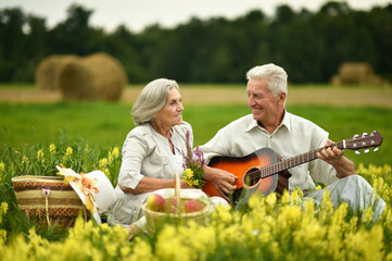 Senior couple with guitar at summer field