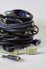 Pile of different coiled computer cables on white background.