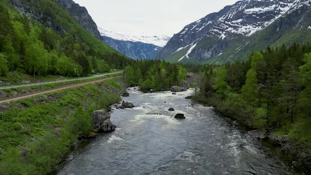 Rauma River in Romsdalen, Rauma Norway, with massive boulders, surrounded by evergreen trees and sno