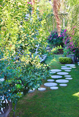 Round white marble walkway with black gravel in the garden of a house with tropical vegetation