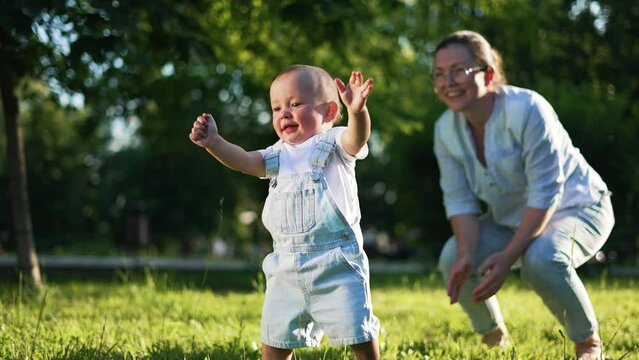 Happy family. Baby takes first steps with his parents.First steps on picnic in park on green grass,baby plays with his mother and father.Fun in summer in park on grass.First steps in spring happy days