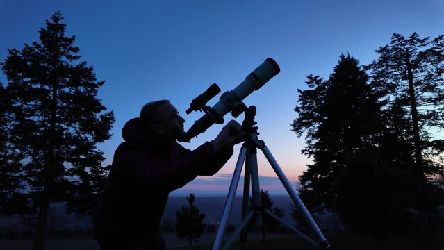 Amateur astronomer looking at the evening skies, observing planets, stars, Moon and other celestial objects with a telescope.	
