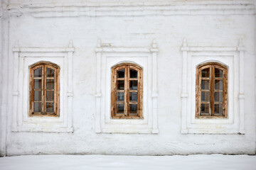 Fototapeta na wymiar Wall with three windows of old whitewashed house on winter day.