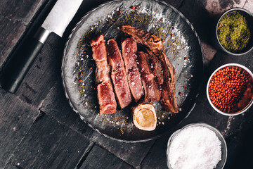 Succulent Farmhouse Rustic Rump Steak with thyme garnish shot against a dark background with wood burner. The perfect image for your bistro or restaurant menu cover art. Copy space.