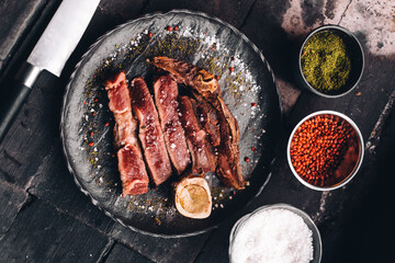 Succulent Farmhouse Rustic Rump Steak with thyme garnish shot against a dark background with wood burner. The perfect image for your bistro or restaurant menu cover art. Copy space.