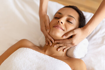 Obraz na płótnie Canvas therapist rubbing relaxed woman's chin during facial massage at spa