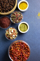 vertical photo of different spices, aromatic spices, spices for the kitchen, on a blue background, copy space