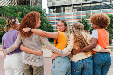 Group of young adult women walking together one of them looks at the camera. Teenage females moving...
