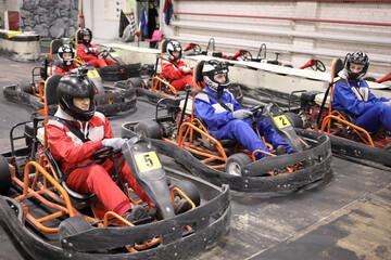 Five adults and one child in helmets prepares for driving karting - obrazy, fototapety, plakaty