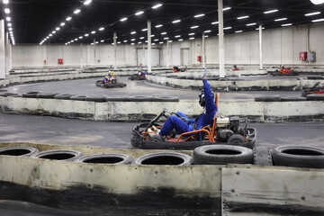 Man in helmet drives in go-kart with raised arm on track during competition, other drivers out of...