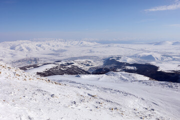 Fototapeta na wymiar Beautiful mountains in snow in ski resort, power plant, Sevan lake far away, Tsakhkadzor, Armenia in winter sunny day