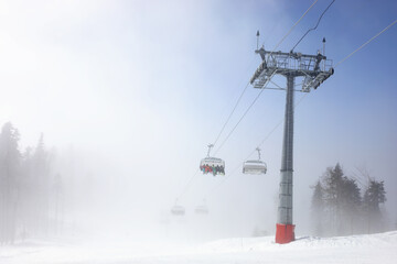Fototapeta na wymiar Cableway in ski resort in mountains in fog in Krasnaya Polyana village, Sochi, Russia