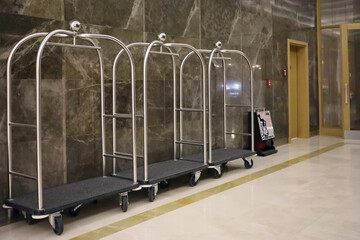 Three luggage carts with wheels near wall in hall in modern hotel