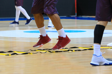 Legs of men in sport shoes and shorts during basketball training in stadium